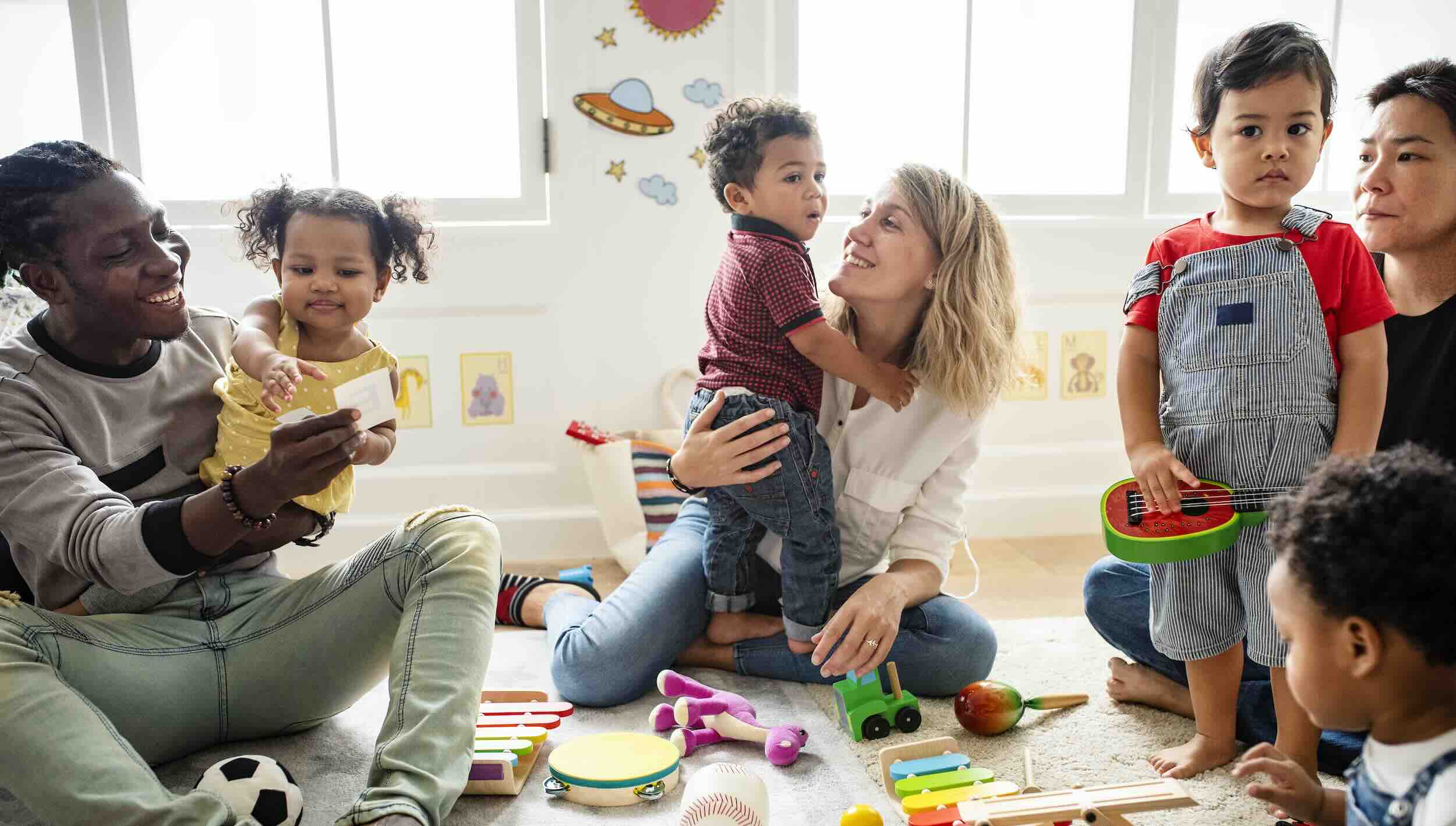 Parents and toddlers playing in bright daycare classroom