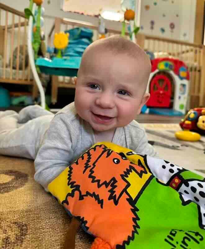 Smiling baby holding colorful soft book toy