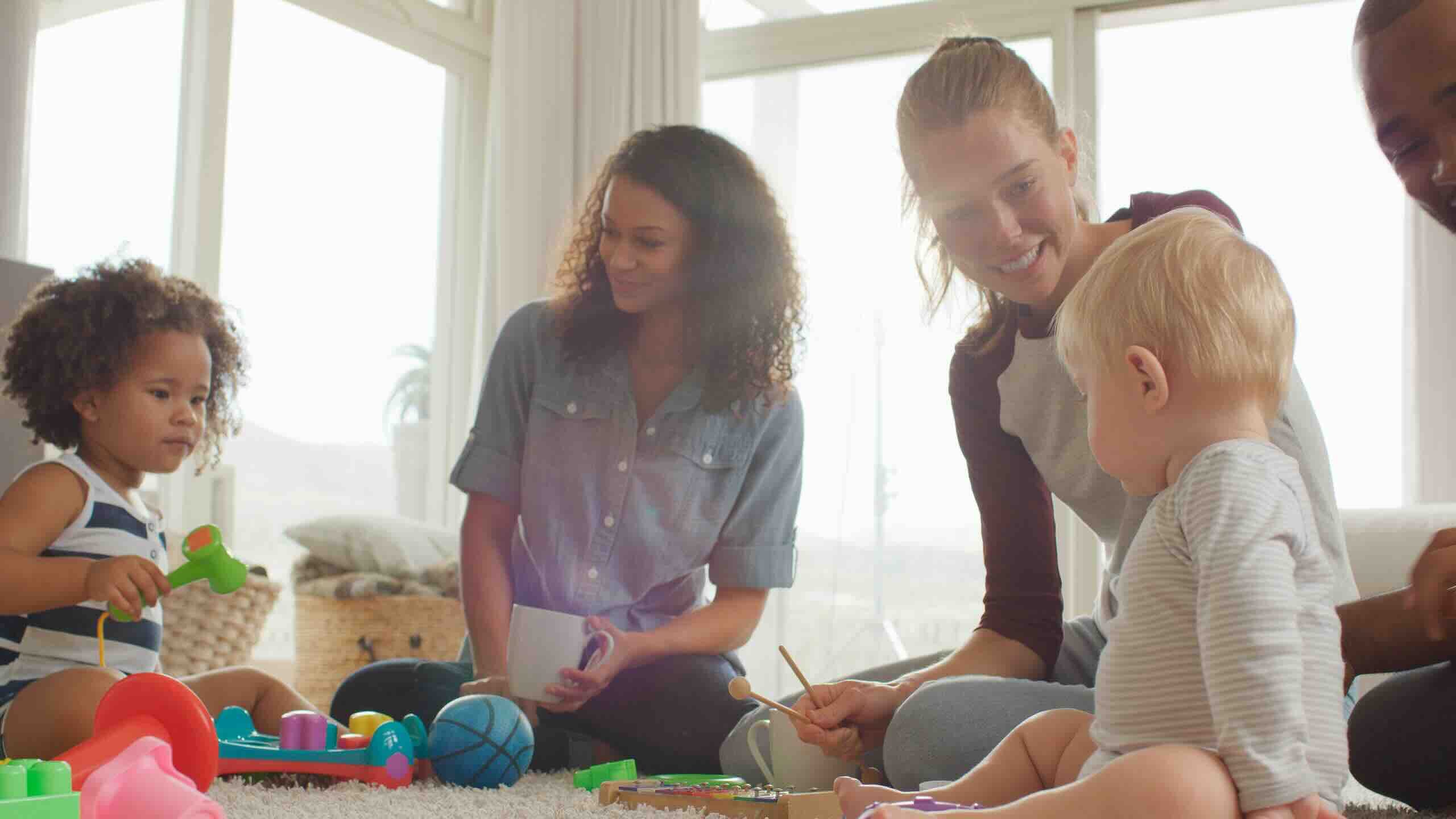 Adults and toddlers playing with toys indoors
