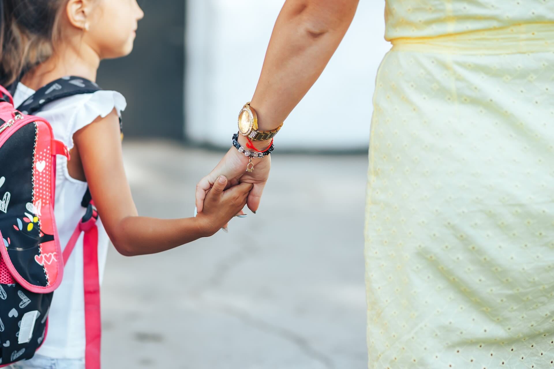 Mother holding daughter's hand on way to school