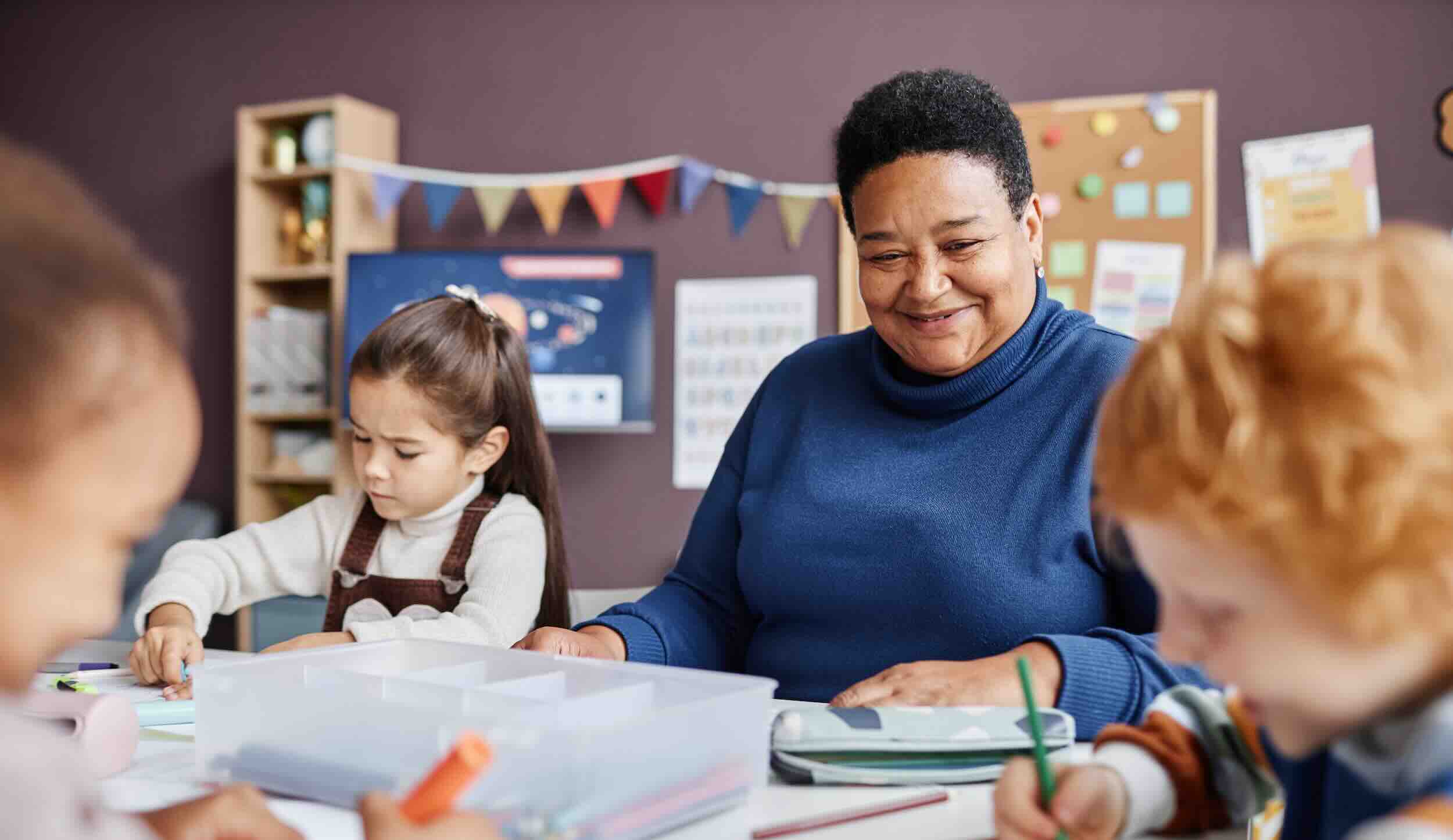 Teacher assisting children with crafts in classroom